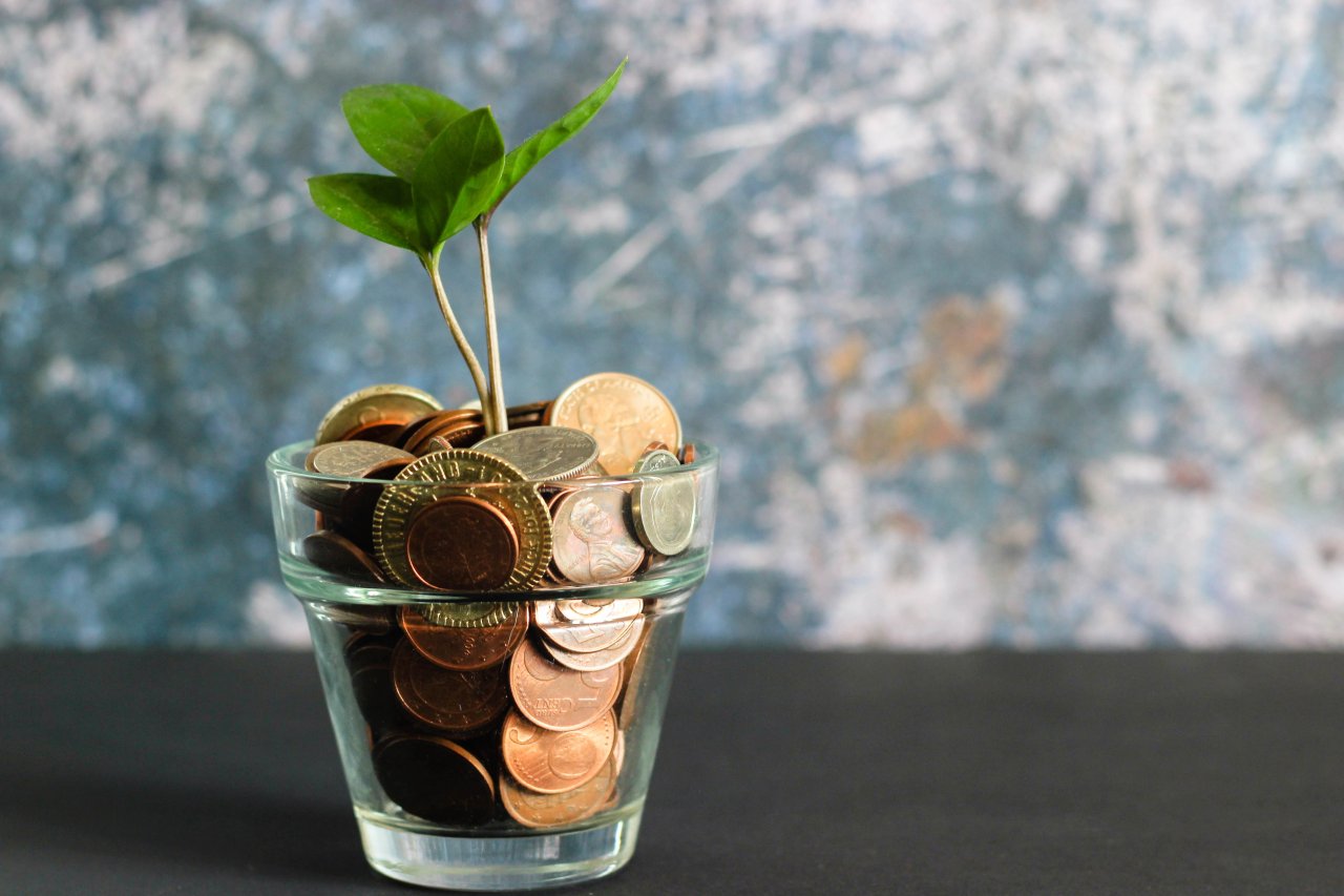 Afbeelding van een glas met geld waar een plant uit groeit.